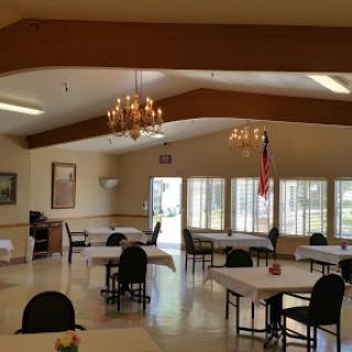 A spacious dining area with tables and chairs, illuminated by chandeliers, providing a welcoming atmosphere.