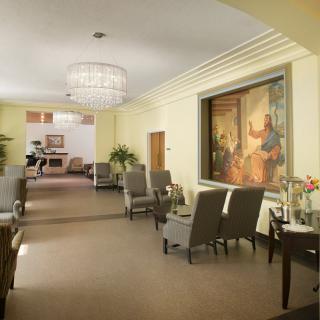A spacious and well-decorated lobby with comfortable seating, a chandelier, and artwork on the wall.