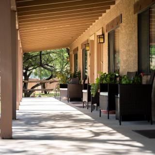 A quiet, shaded porch with outdoor seating and potted plants.