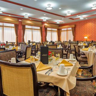 An elegantly set dining room with neatly arranged tables and chairs, ready for guests.