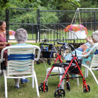 A group of seniors sitting outside in a garden enjoying the day.