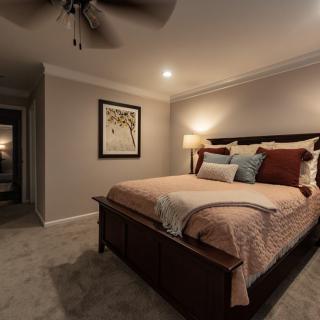 A cozy and well-decorated bedroom with a large bed, soft lighting, and warm tones.