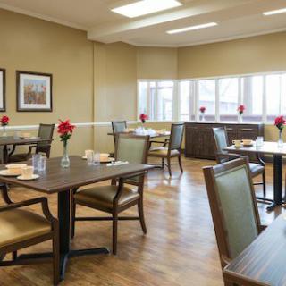 A cozy dining area with tables and chairs set up, decorated with flowers.