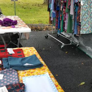 A vibrant market scene featuring tables of colorful fabrics and clothing hanging on a rack.