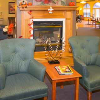 A cozy living room with two chairs facing a fireplace and a small coffee table.