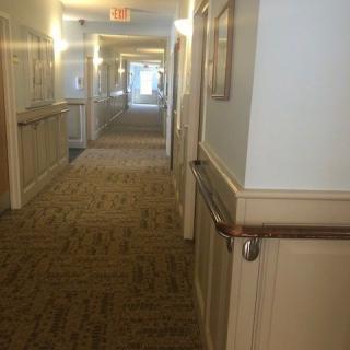 A well-lit corridor with carpeted flooring and handrails along the walls.