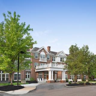 A two-story brick building surrounded by trees under a clear blue sky.
