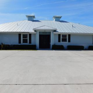 A residential building with a metal roof and a wide driveway.