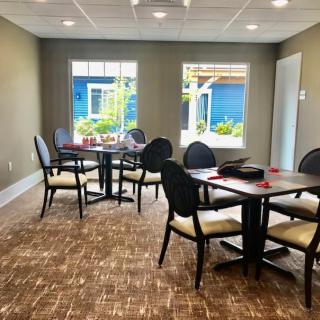 A well-lit dining area with several tables and chairs, featuring large windows that let in natural light.