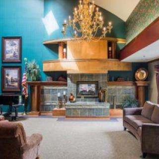 A modern living room with an elegant chandelier and a central fireplace.