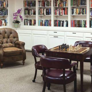 A cozy study room with a chessboard and bookshelves.