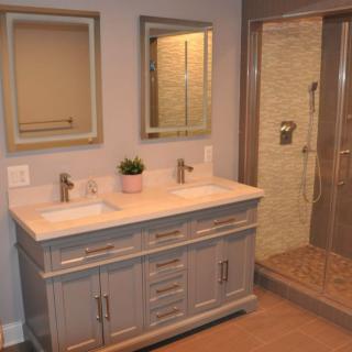 Modern bathroom with double sink vanity and glass-enclosed shower.