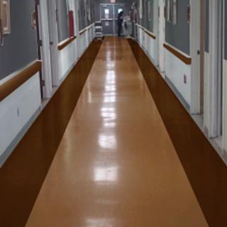 A long hospital corridor with a shiny brown floor.