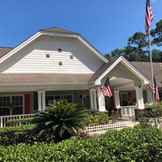 A charming residential building with vibrant landscaping and flags adorning its entrance.
