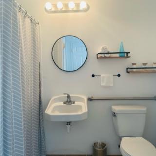 A modern and clean bathroom featuring a round mirror, sink, and neatly arranged shelves.