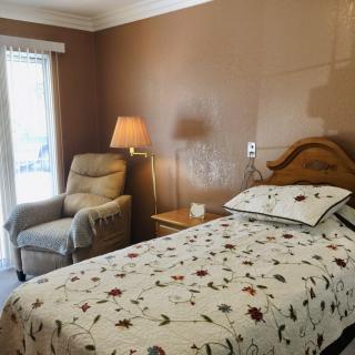 A cozy bedroom with a single bed, armchair, and a lamp by the window.
