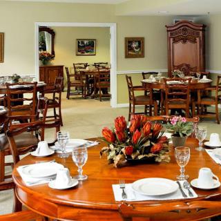 An elegantly set dining room with polished wooden tables and floral arrangements.