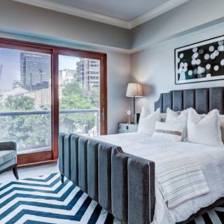 A modern bedroom with a city view, featuring a stylish chevron rug and contemporary decor.