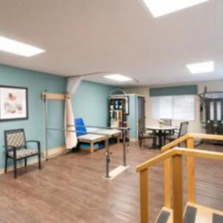 A well-lit rehabilitation room equipped with various physical therapy tools and furniture.