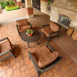 Outdoor seating area with chairs and a table on brick flooring, featuring a fireplace.