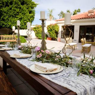 An elegant outdoor dining setup with candles and floral arrangements on a patio.
