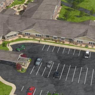 An aerial view of a large building with a parking lot and surrounding green spaces.