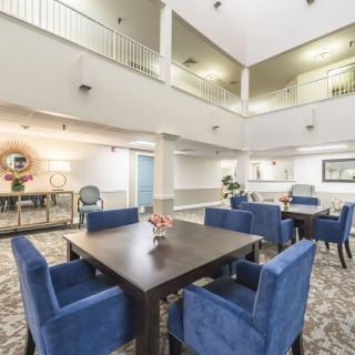 A modern dining area with blue upholstered chairs surrounding a dark wood table, set in an open and well-lit interior space.