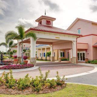 A tropical-themed hotel entrance with palm trees and colorful landscaping.