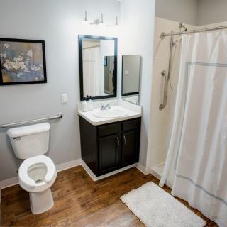 A modern and clean bathroom with a toilet, sink, mirror, and shower.