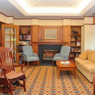 A cozy living room with a fireplace, armchairs, a sofa, and bookshelves.