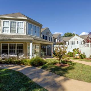 A charming residential house with a well-maintained garden and clear blue skies.