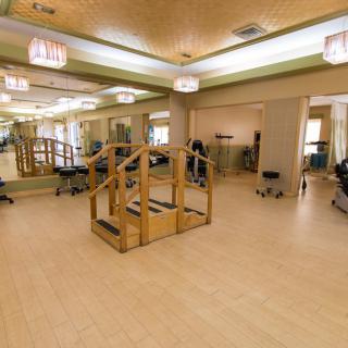 A spacious rehabilitation therapy room with various exercise equipment.