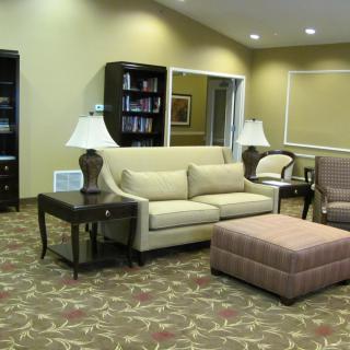 A cozy living room with a sofa, chairs, and a coffee table, decorated with lamps and a carpet.