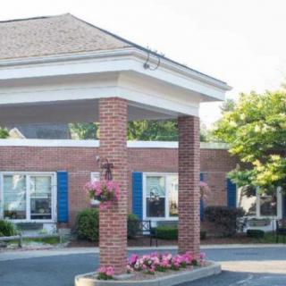 A brick building entrance with an awning and decorative landscaping.