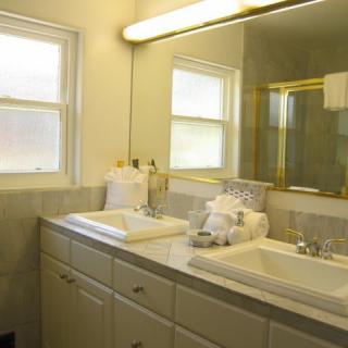 A clean and tidy bathroom with a double sink, large mirror, and neatly folded towels.