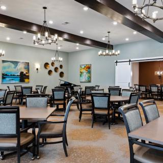 A modern dining room featuring elegantly arranged tables and chairs, adorned with chandeliers and contemporary artwork.