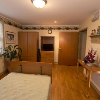 A cozy bedroom with wooden furniture, including a wardrobe and bed, decorated with plants and flowers.