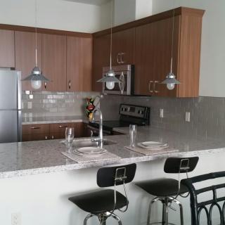 A modern kitchen with a sleek countertop, bar stools, and pendant lighting.