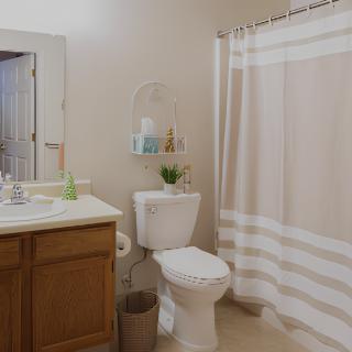 A clean and organized bathroom with a sink, toilet, and shower.