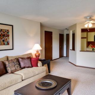 A cozy living room featuring a sofa, stylish lamp, and an open layout that connects to the kitchen area.