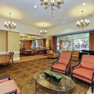A spacious and elegantly decorated lobby with comfortable seating, chandeliers, and large windows.