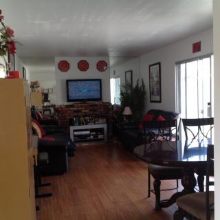 A cozy living room with a television and sofa set, complemented by a dining area in the foreground.