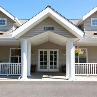 A front view of a residential building's entrance with white columns and railings.