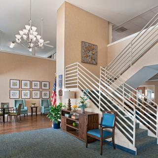 A modern lobby with a staircase, chandelier, and seating area.