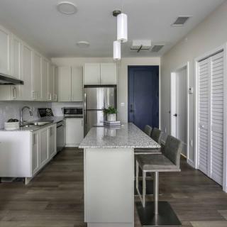 A modern kitchen with white cabinets, stainless steel appliances, and a central island with pendant lighting.