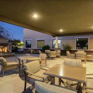Cozy outdoor patio with seating and a fireplace, illuminated in the evening.