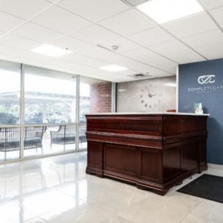 Modern office reception area with a wooden desk and seating.
