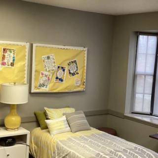 A cozy bedroom with yellow-themed decor and artwork above the bed.