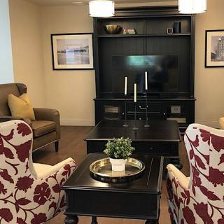 A cozy living room with floral armchairs, a dark entertainment center, and tasteful home decor.