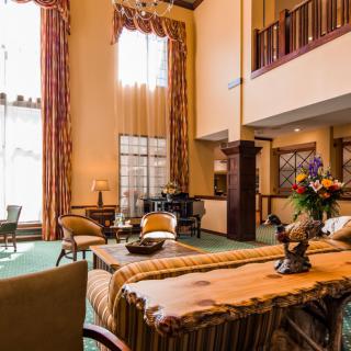 A luxurious living room with high ceilings, elegant furniture, and a grand chandelier.